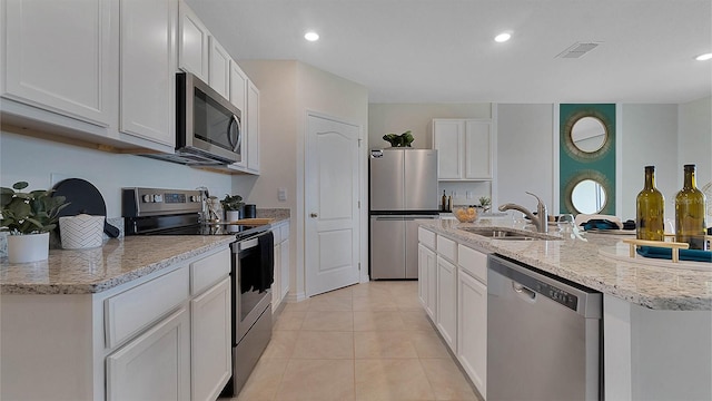 kitchen with white cabinetry, sink, light stone countertops, light tile patterned floors, and appliances with stainless steel finishes