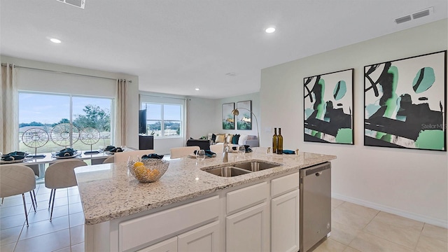 kitchen with light stone countertops, a kitchen island with sink, sink, dishwasher, and white cabinetry