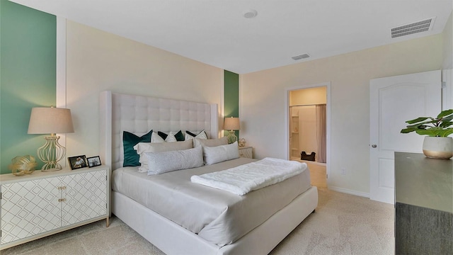 bedroom with ensuite bathroom and light colored carpet