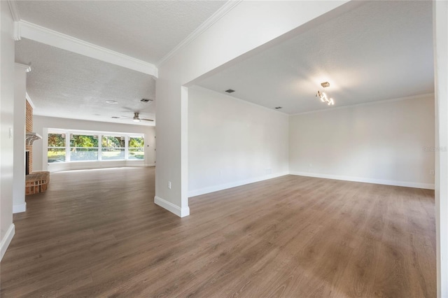 spare room with hardwood / wood-style floors, crown molding, a brick fireplace, ceiling fan, and a textured ceiling