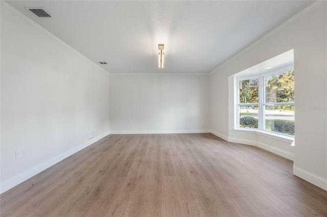 empty room featuring light wood-type flooring and ornamental molding