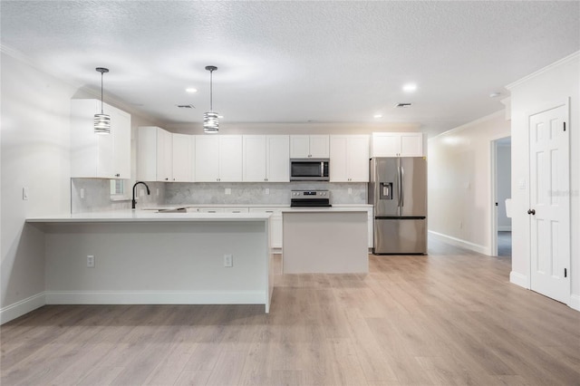 kitchen with white cabinetry, sink, stainless steel appliances, light hardwood / wood-style floors, and decorative light fixtures