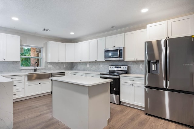 kitchen featuring white cabinetry, sink, wood-type flooring, and appliances with stainless steel finishes