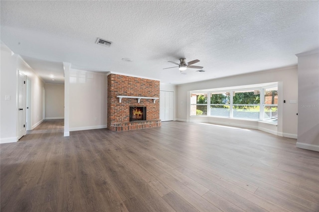 unfurnished living room with ceiling fan, a fireplace, dark wood-type flooring, and a textured ceiling