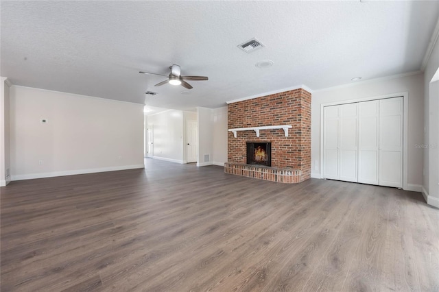 unfurnished living room with crown molding, a brick fireplace, hardwood / wood-style flooring, ceiling fan, and a textured ceiling