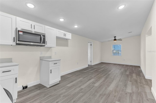 kitchen with white cabinets, light wood-type flooring, and ceiling fan