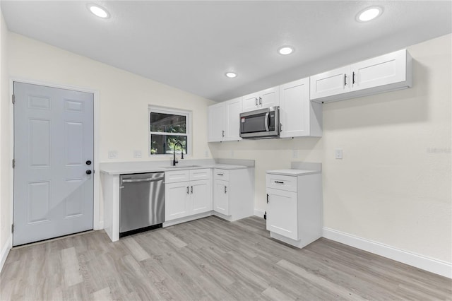 kitchen with stainless steel appliances, white cabinetry, light hardwood / wood-style floors, and sink