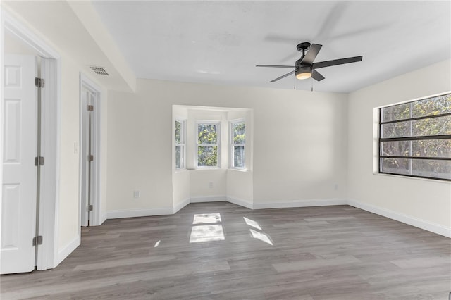 unfurnished room featuring a wealth of natural light, ceiling fan, and light wood-type flooring