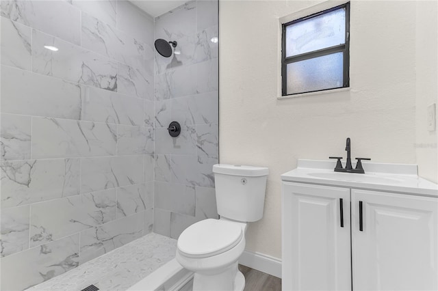 bathroom featuring tiled shower, wood-type flooring, vanity, and toilet