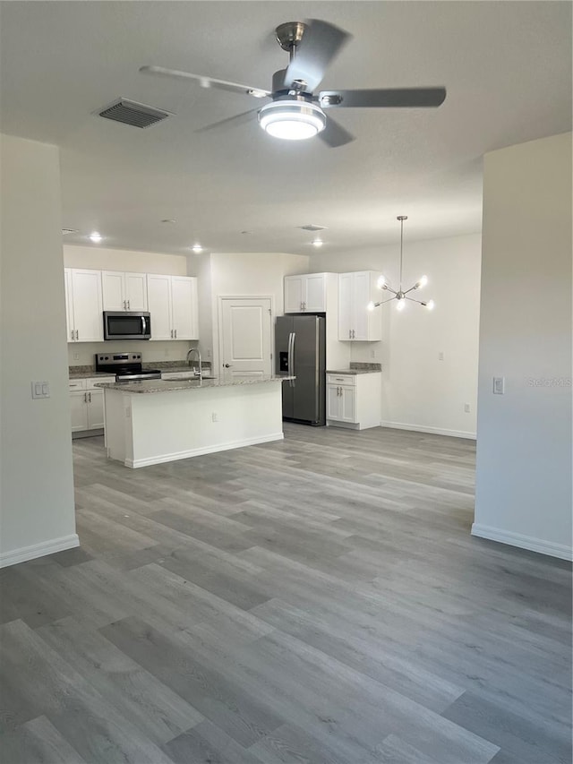 kitchen with white cabinets, appliances with stainless steel finishes, a center island with sink, and light hardwood / wood-style floors