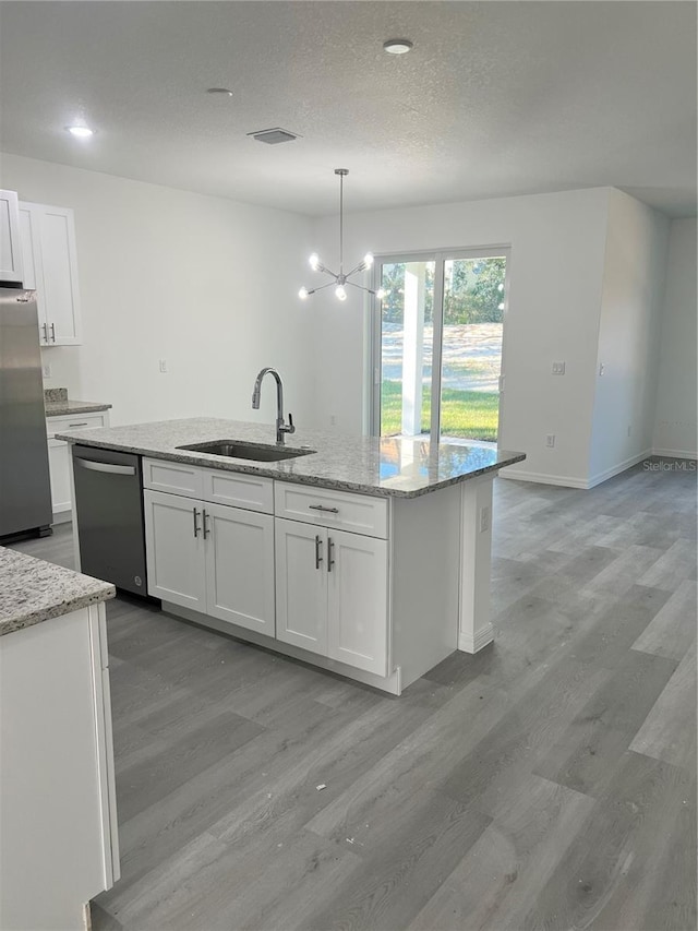 kitchen featuring white cabinets, sink, light stone countertops, appliances with stainless steel finishes, and decorative light fixtures