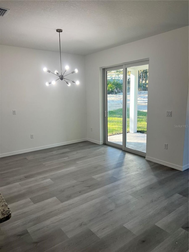 spare room with hardwood / wood-style floors and an inviting chandelier