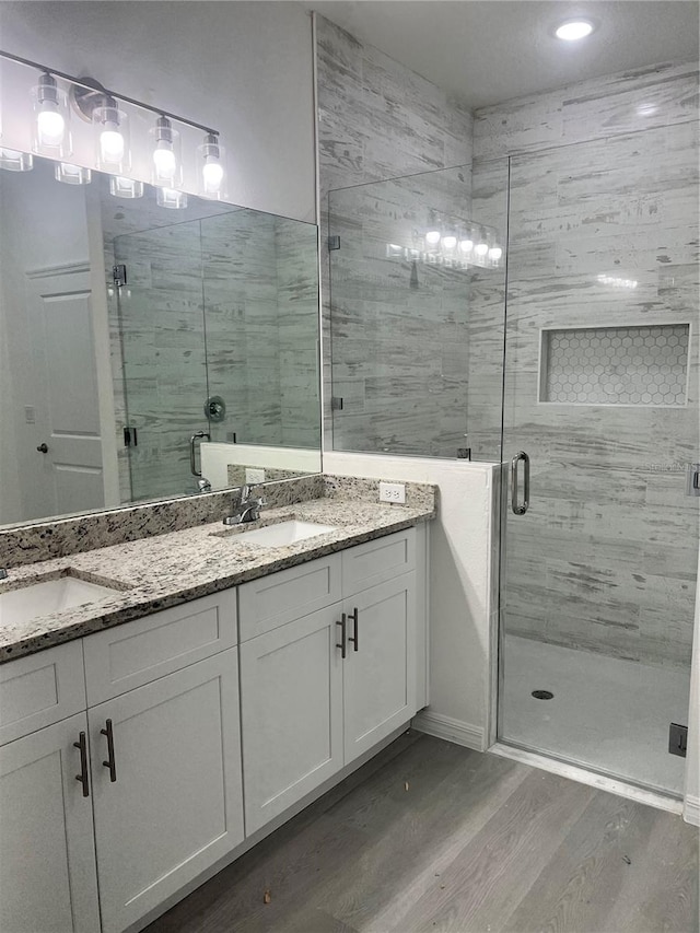 bathroom with hardwood / wood-style flooring, vanity, and an enclosed shower