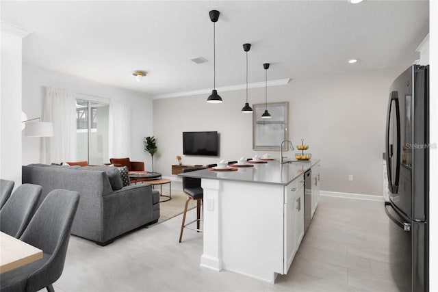 kitchen featuring a kitchen island with sink, white cabinets, sink, hanging light fixtures, and stainless steel appliances