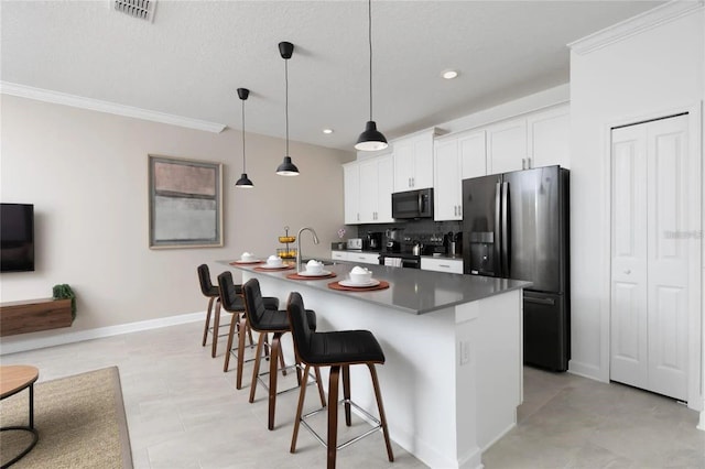 kitchen featuring white cabinets, stainless steel appliances, a center island with sink, and a breakfast bar area