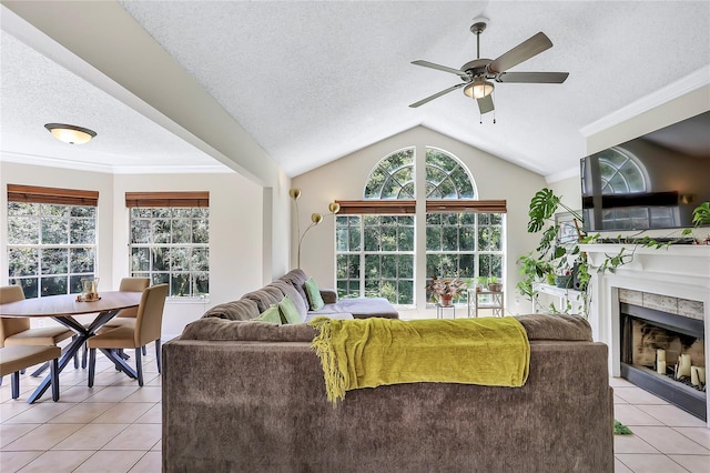 tiled living room with ornamental molding, a textured ceiling, ceiling fan, a tile fireplace, and lofted ceiling