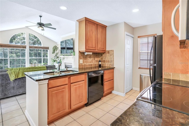 kitchen featuring dark stone counters, black appliances, sink, vaulted ceiling, and ceiling fan