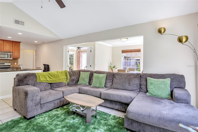 tiled living room with ceiling fan, a healthy amount of sunlight, lofted ceiling, and sink