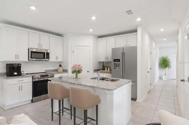 kitchen with white cabinets, stainless steel appliances, a center island with sink, and sink