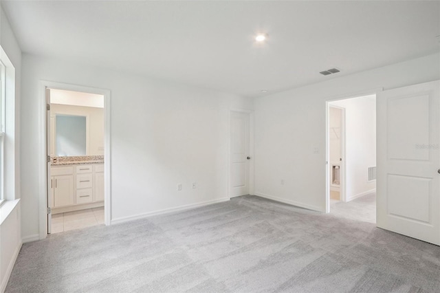 unfurnished bedroom with light carpet and connected bathroom