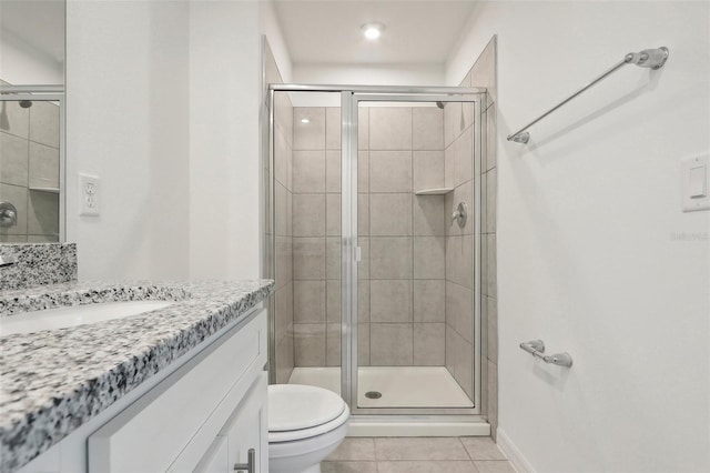 bathroom with tile patterned floors, a shower with door, vanity, and toilet