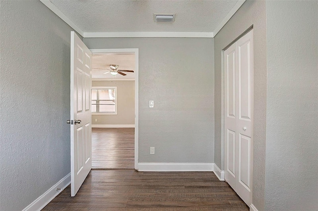 hallway with a textured ceiling, dark hardwood / wood-style floors, and crown molding