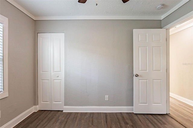 unfurnished bedroom featuring a textured ceiling, dark hardwood / wood-style flooring, a closet, and ceiling fan