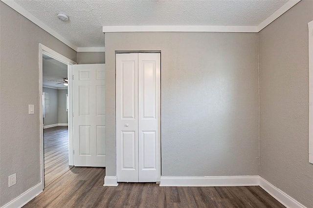 unfurnished bedroom featuring a textured ceiling, a closet, and dark hardwood / wood-style floors