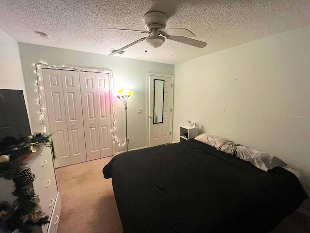 bedroom with ceiling fan, a closet, light carpet, and a textured ceiling