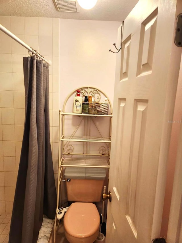 bathroom featuring toilet, a shower with shower curtain, and a textured ceiling