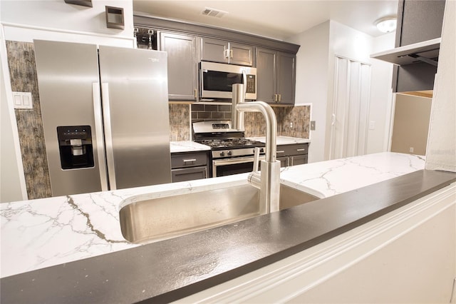 kitchen featuring light stone countertops, appliances with stainless steel finishes, and backsplash