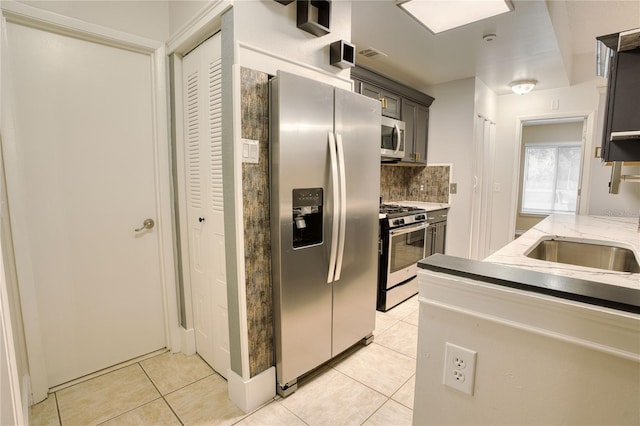 kitchen featuring decorative backsplash, sink, light tile patterned floors, and stainless steel appliances