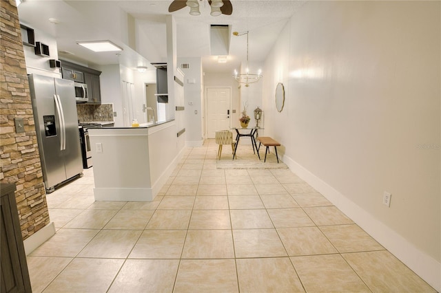 kitchen with kitchen peninsula, appliances with stainless steel finishes, hanging light fixtures, and light tile patterned flooring