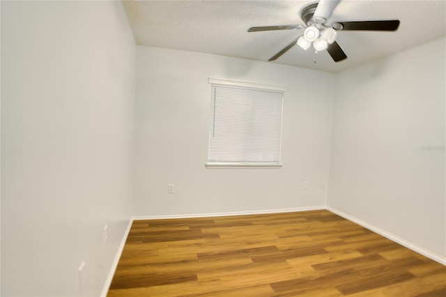 empty room with ceiling fan, wood-type flooring, and a textured ceiling