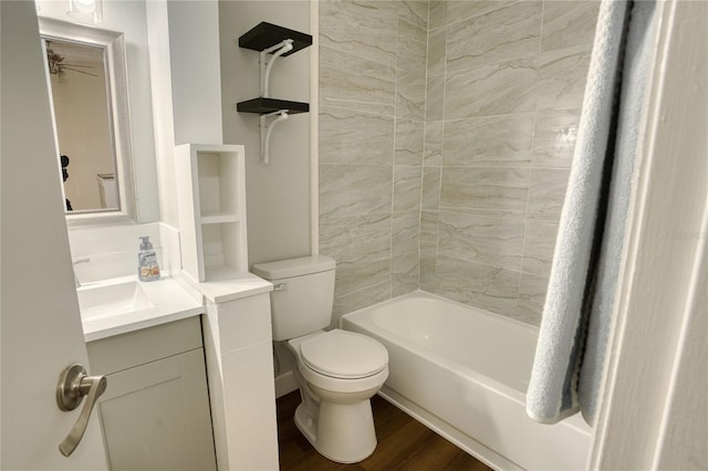 full bathroom with tiled shower / bath, vanity, wood-type flooring, and toilet