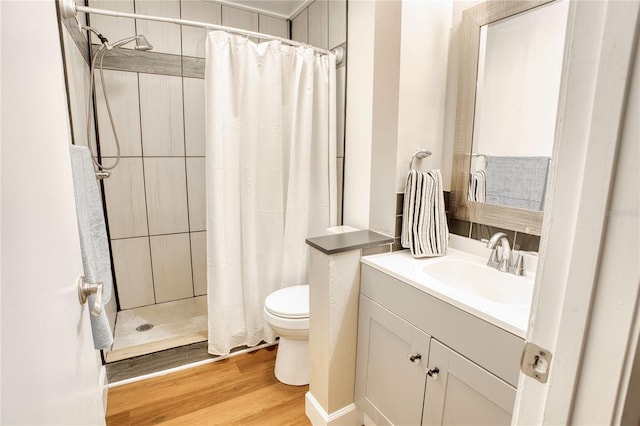 bathroom featuring wood-type flooring, vanity, toilet, and walk in shower