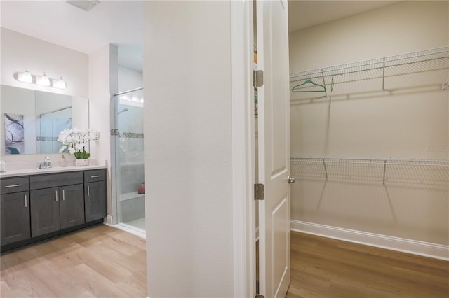 interior space featuring a shower with door, vanity, and hardwood / wood-style flooring