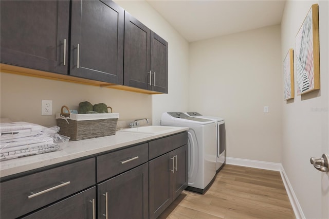 washroom featuring cabinets, independent washer and dryer, light wood-type flooring, and sink