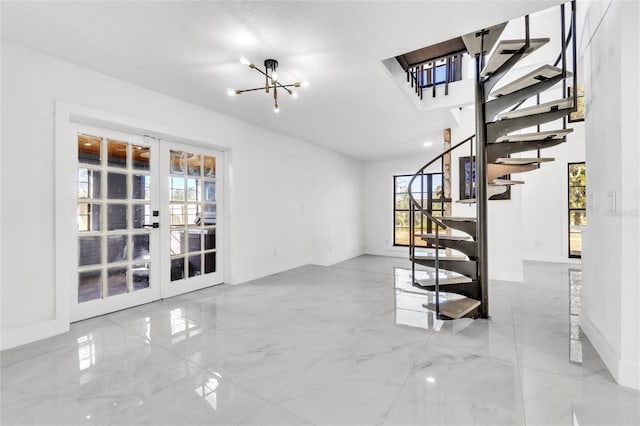 unfurnished living room featuring a chandelier and french doors