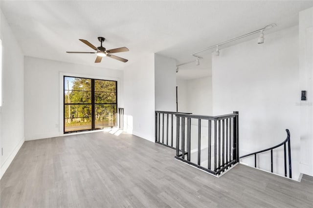 spare room featuring ceiling fan, track lighting, and light wood-type flooring