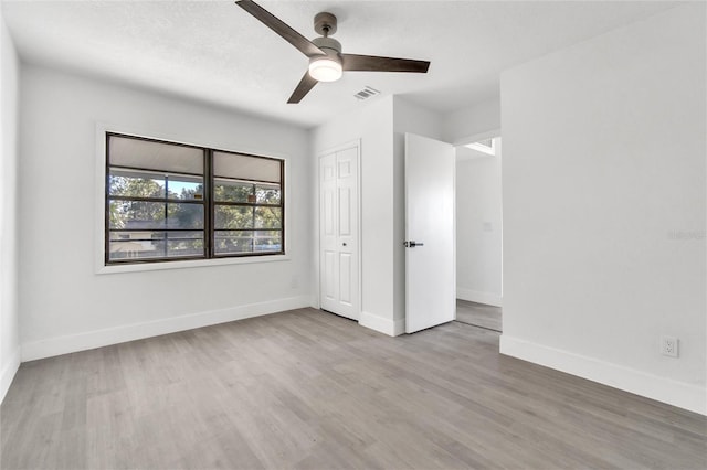 unfurnished bedroom featuring a textured ceiling, light hardwood / wood-style floors, a closet, and ceiling fan