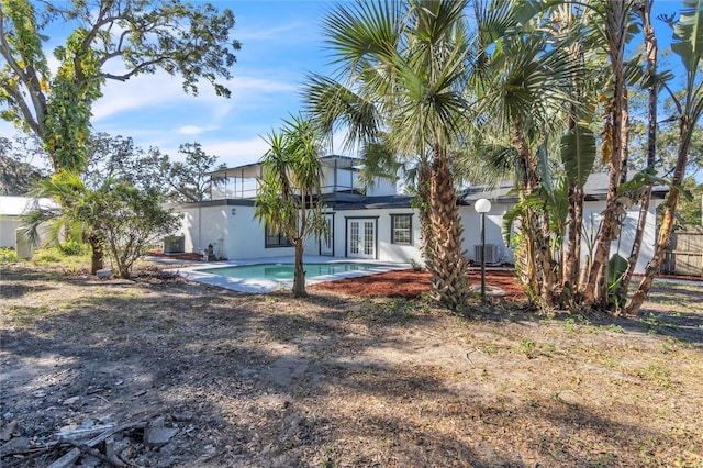 rear view of property with french doors, a fenced in pool, and cooling unit