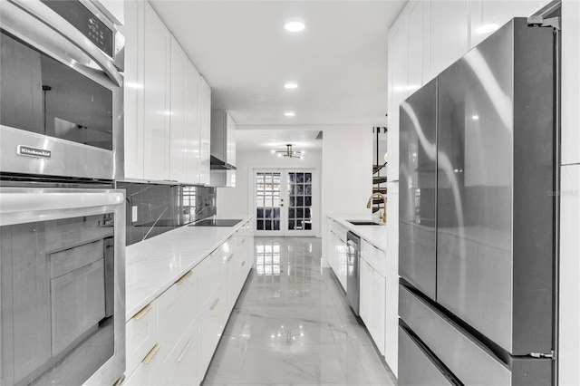 kitchen with tasteful backsplash, appliances with stainless steel finishes, sink, and white cabinets