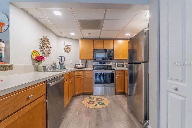 151 E Washington St Unit 201, Orlando, FL 32801 - kitchen with appliances with stainless steel finishes, light wood finished floors, a drop ceiling, light countertops, and brown cabinets