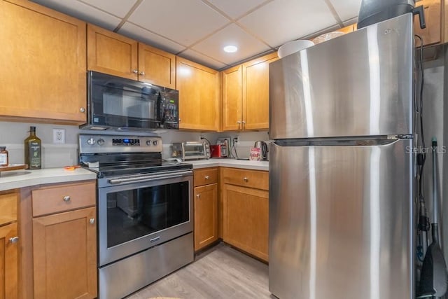 kitchen featuring a drop ceiling, light wood-type flooring, and appliances with stainless steel finishes