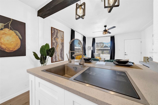 kitchen featuring dark wood-type flooring, white cabinets, sink, ceiling fan, and beamed ceiling