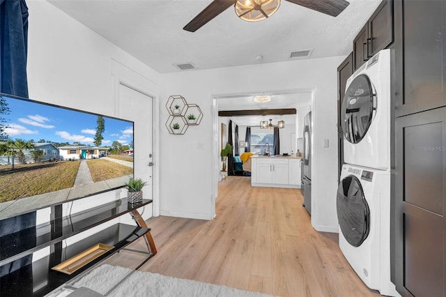 laundry area with ceiling fan with notable chandelier, stacked washer / drying machine, and light wood-type flooring