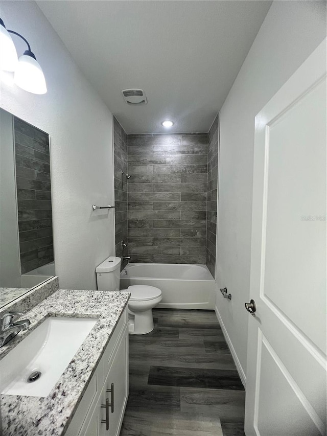 full bathroom featuring hardwood / wood-style floors, vanity, toilet, and tiled shower / bath