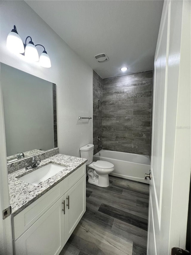 full bathroom featuring tiled shower / bath combo, a textured ceiling, toilet, vanity, and hardwood / wood-style flooring