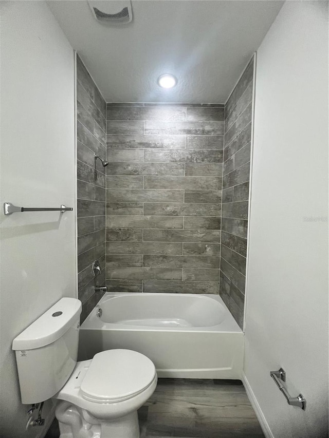 bathroom featuring toilet, wood-type flooring, and tiled shower / bath